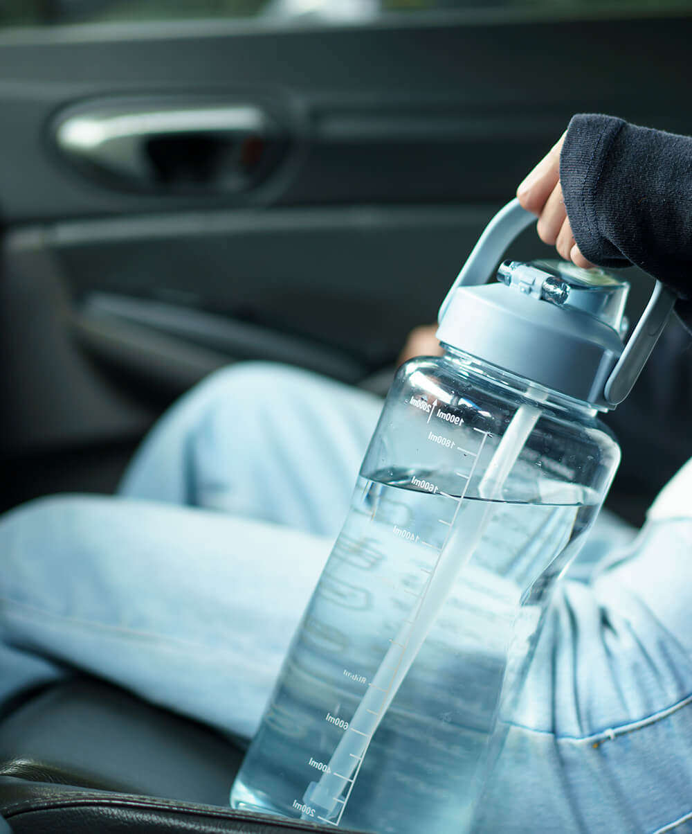 Hand holding large water bottle in car seat