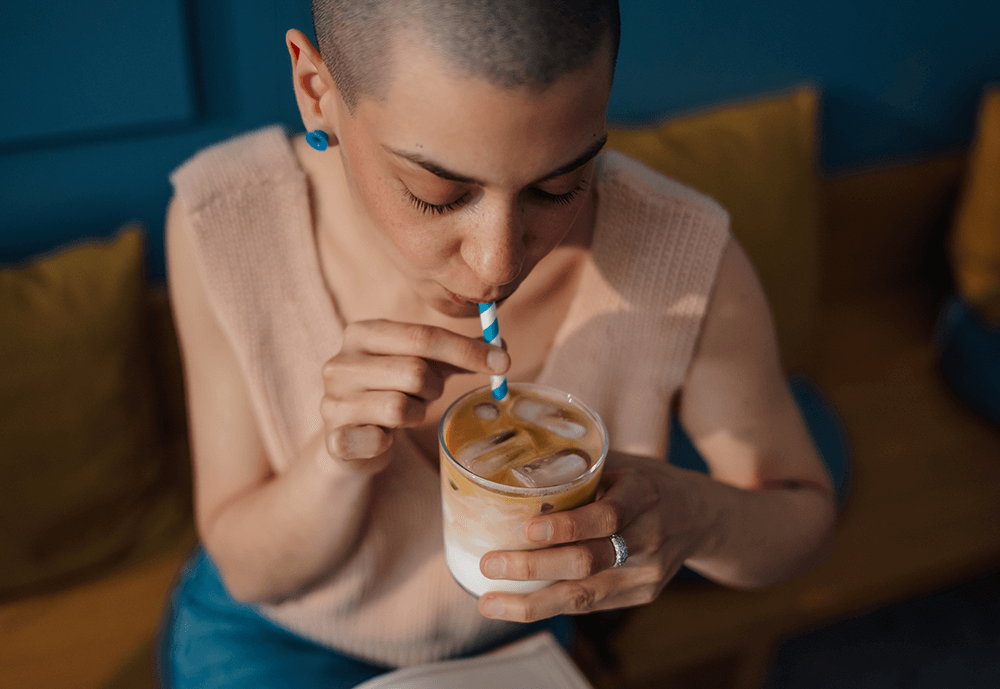 Person sipping iced coffee through a striped straw