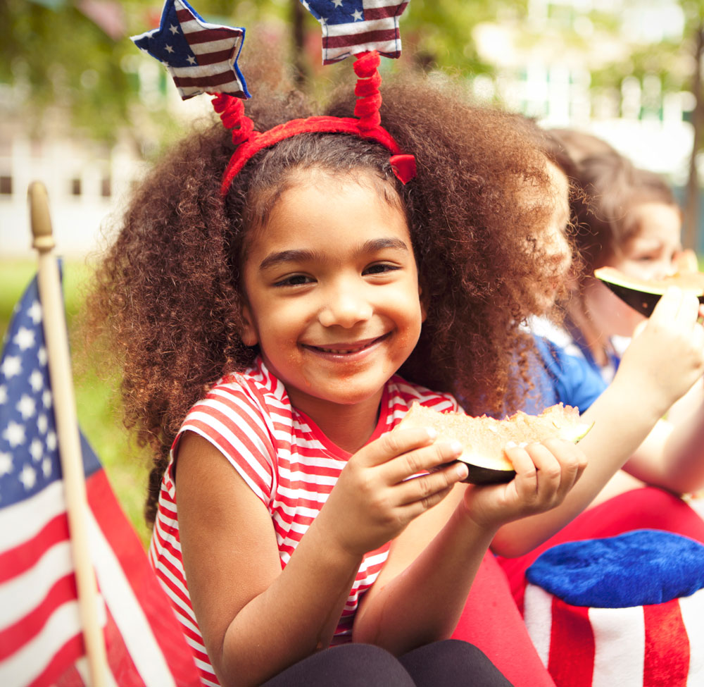 Girl with patriotic headband eating watermelon outdoors