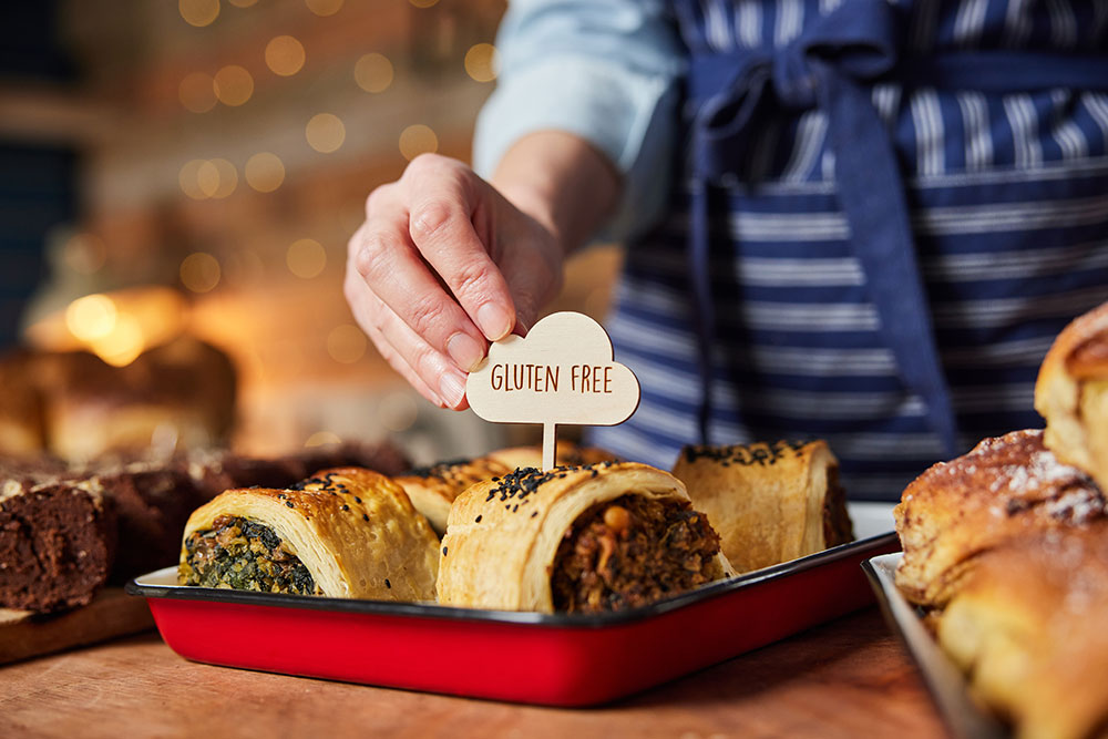 Hand placing gluten-free label on baked goods