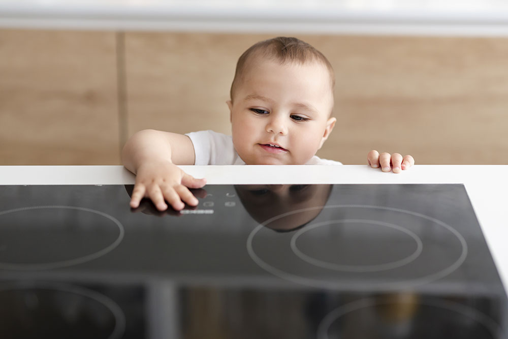 Baby reaching towards induction stove with curiosity