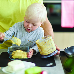 Child helping spoon food into a container