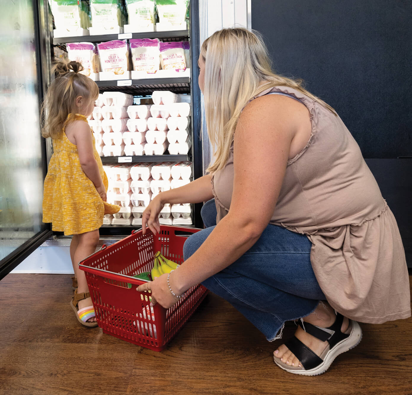 Woman and child selecting eggs at grocery store.