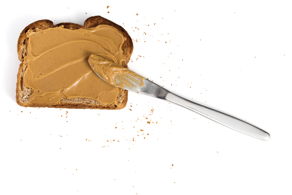 Peanut butter spread on toast with knife.