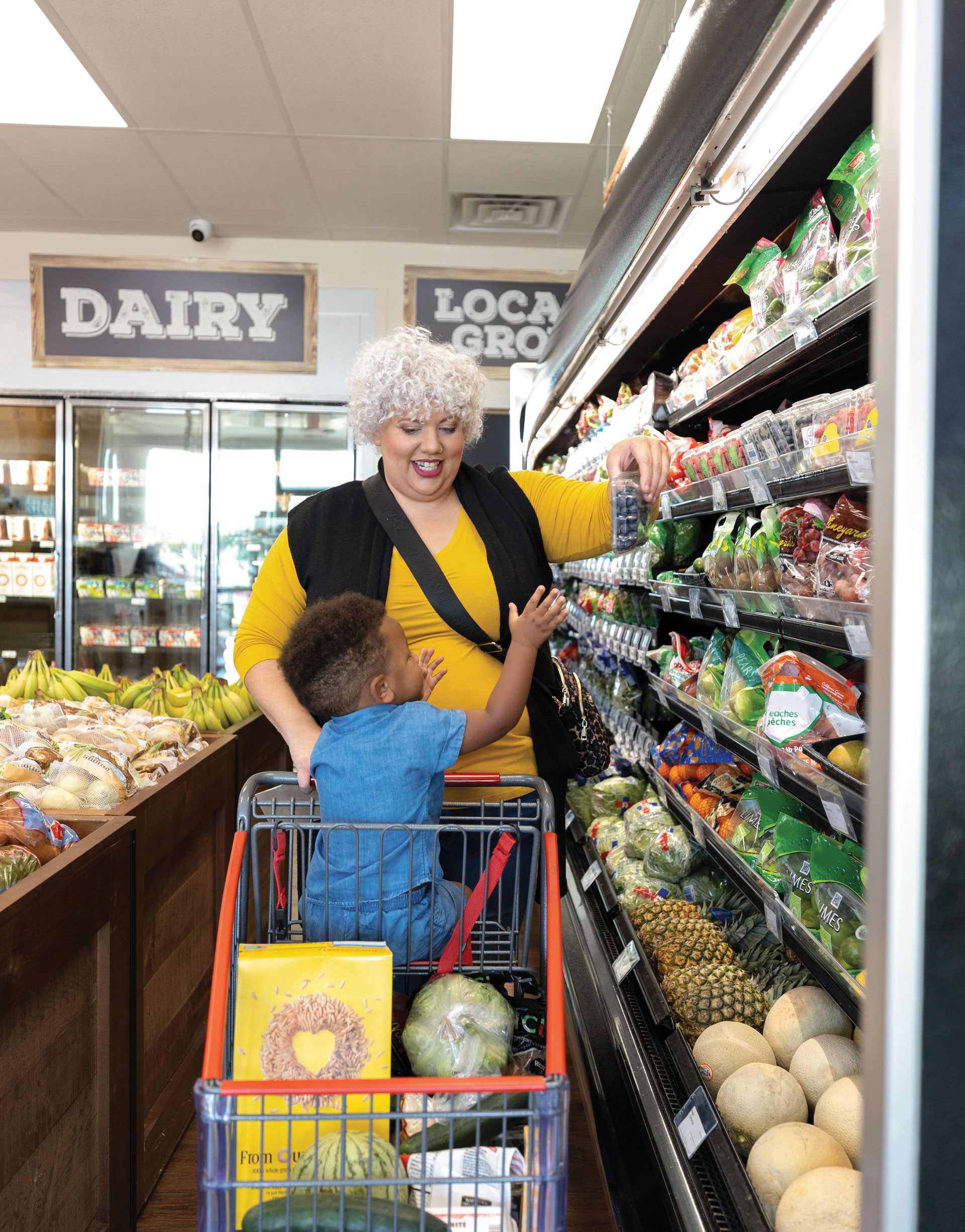 Woman and child shopping for produce together happily.