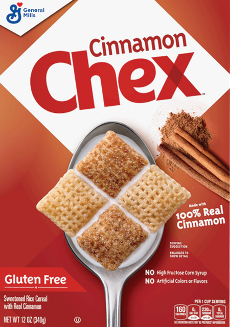 Cereal squares on spoon with cinnamon sticks nearby.